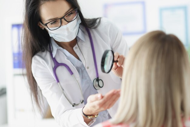 Médico examinando a pele do rosto do paciente usando uma lupa. conceito de exame de pele