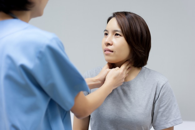 Foto médico está examinando el cuello lesionado del paciente femenino