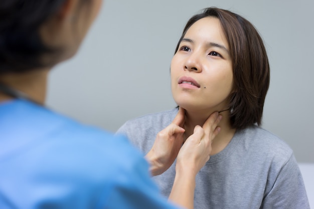 Foto médico está examinando el cuello lesionado del paciente femenino