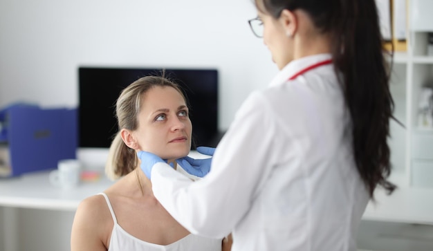 Médico examinando los ganglios linfáticos submandibulares de los pacientes en la clínica