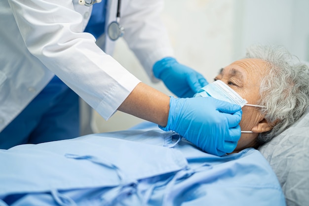 Médico examinando paciente asiática sênior usando uma máscara facial para proteger o Covid-19 Coronavirus.