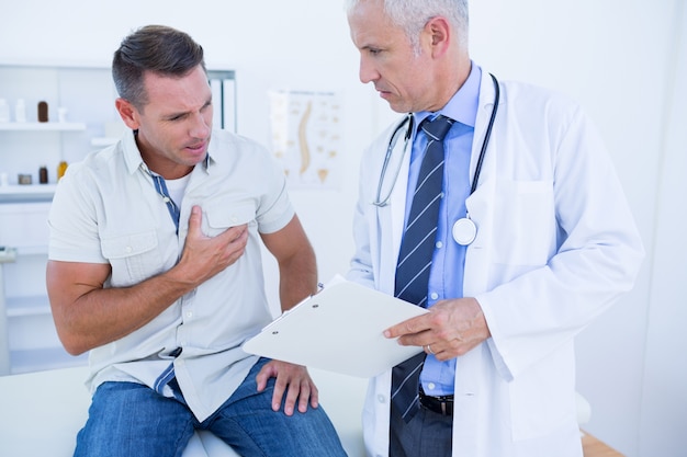Médico examinando seu paciente e escrevendo na prancheta