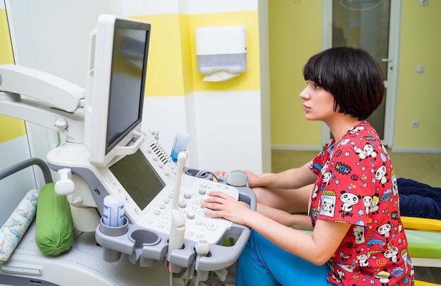 Médico examinando um menino com equipamento ultrassônico no hospital.
