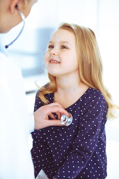 Médico examinando um paciente infantil pelo estetoscópio. Menina bonita na consulta médica. Conceito de medicina. Foto tonificada