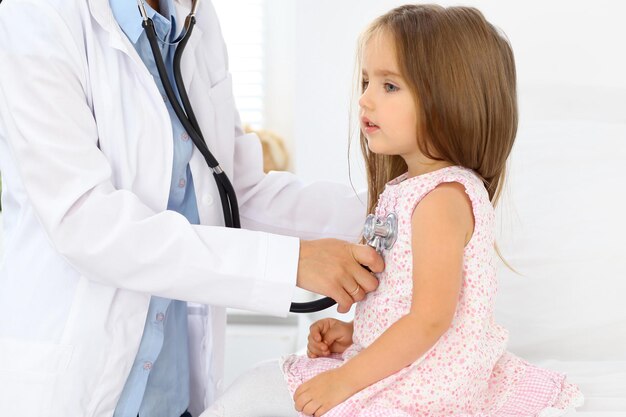 Médico examinando uma garotinha pelo estetoscópio.