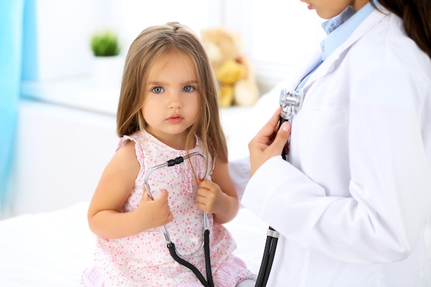 Médico examinando uma garotinha pelo estetoscópio.