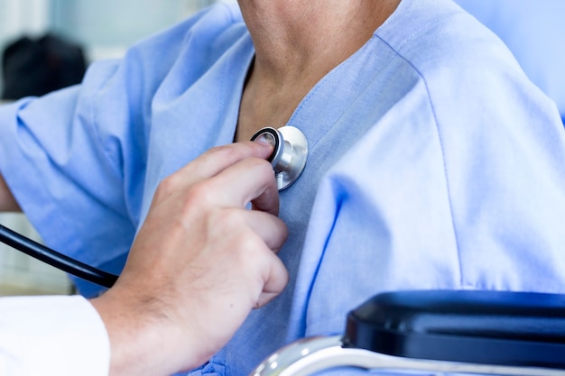 Médico examinou o corpo usando os fones de ouvido, o batimento cardíaco do paciente do sexo feminino no hospital.