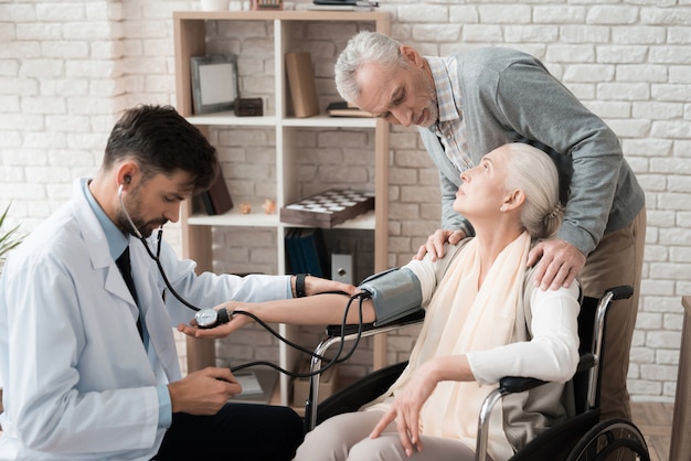 Médico experiente com tonometer ajuda velha.