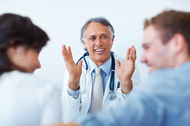 Médico explicando a seus pacientes Retrato de médico maduro feliz explicando a seus pacientes jovens