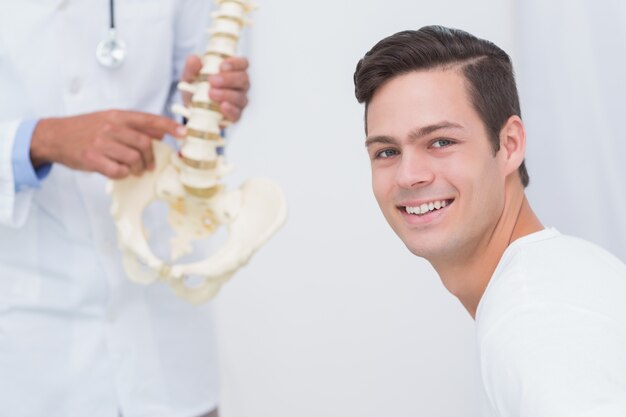 Médico explicando la columna vertebral anatómica a su paciente