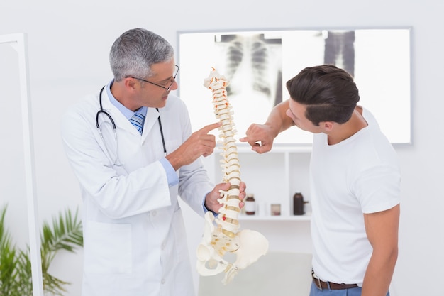 Médico explicando la columna vertebral anatómica a su paciente