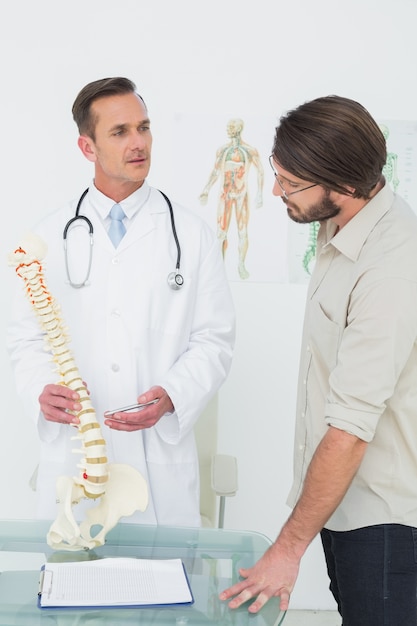 Médico explicando la columna vertebral a un paciente