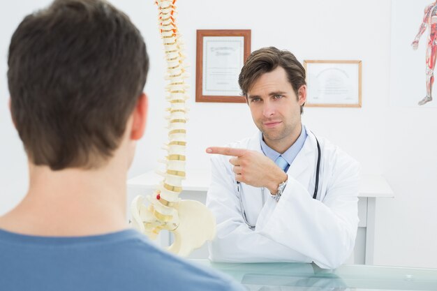 Médico explicando la columna vertebral a un paciente