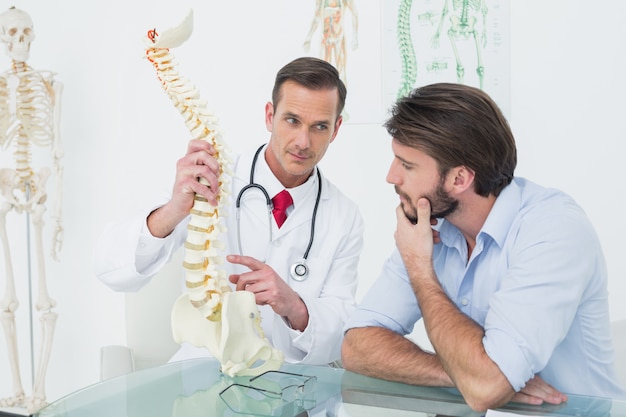 Médico explicando la columna vertebral a un paciente