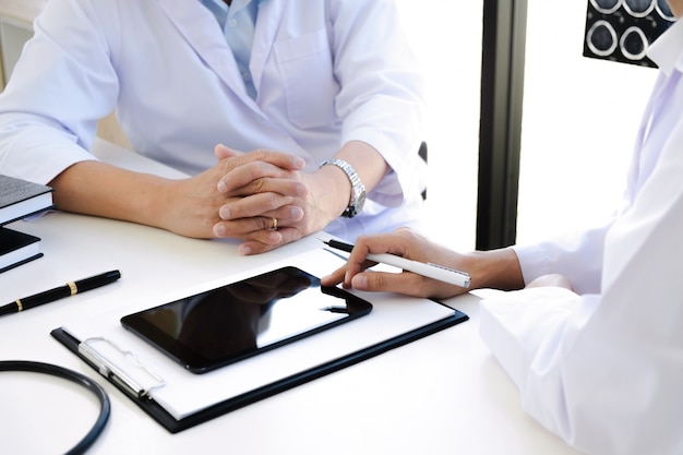 Médico explicando consultor con películas de rayos X en la sala de consulta