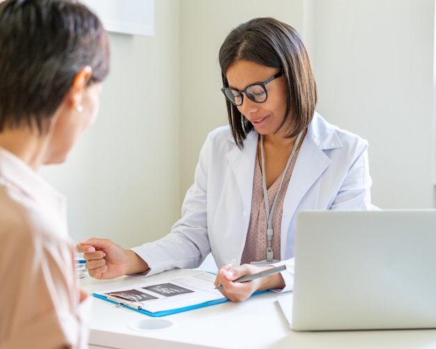 Foto médico explicando el diagnóstico a la prescripción y el tratamiento del paciente femenino sin rostro