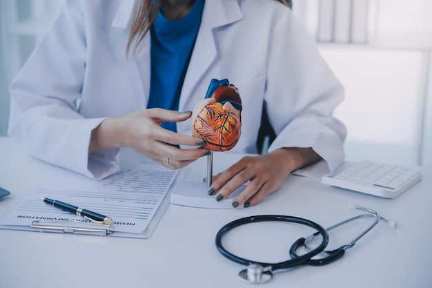 Médico explicando o coração a um paciente idoso Médico explicado o modelo de coração Médicos apontam a caneta para um modelo de coração