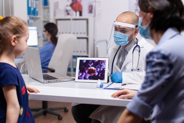 Médico explicando sobre coronavírus à mãe durante a consulta com o filho