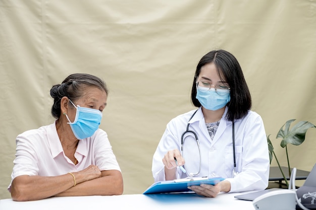 El médico explicó los resultados del examen de salud al anciano en el hospital de campaña. Ambos usaban máscaras debido a la epidemia de covid 19.