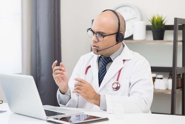 Médico fala com o paciente por videoconferência online com computador portátil usando fone de ouvido Explicar sobre tomar medicamentos para tratar doenças