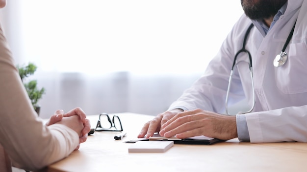 Foto médico de familia y paciente hablando en consultorio médico.