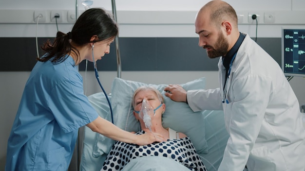 Médico fazendo consulta com paciente aposentado para cuidados de saúde na enfermaria do hospital. Médico falando com mulher doente enquanto enfermeira dando suporte para exame médico e recuperação. Equipe médica