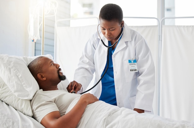 Médico fazendo exame de saúde do coração no paciente na cama ouvindo batimentos cardíacos saudáveis e consultando homem negro após cirurgia no hospital Homem doente fazendo testes com profissional de saúde