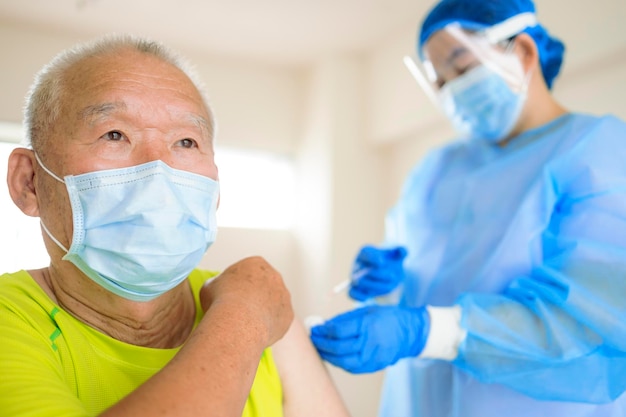 Médico fazendo injeção de vacina para homem sênior