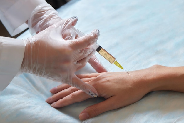 Médico fazendo terapia com células-tronco no cotovelo de um paciente após a lesão tratando dor no joelho com plaquetas