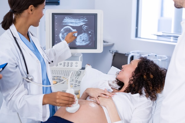 Médico fazendo ultra-sonografia para mulher grávida