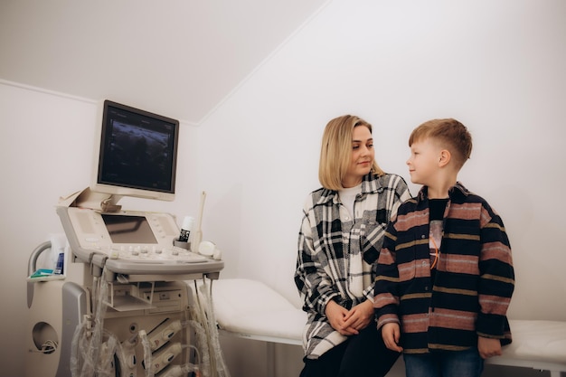 Foto médico fazendo ultrasonografia a um paciente menino no consultório de ultrassom da clínica médica diagnóstico por ultrassom de glândula tireóide para crianças