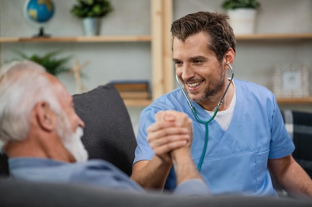 Médico feliz e paciente sênior se cumprimentando virilmente durante uma visita domiciliar