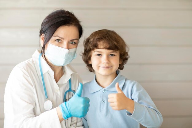 Médico feliz e seu menino paciente sorriem e olham para a câmera