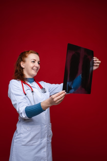 Médico feliz con rayos X de pulmón. Aislar en la pared roja