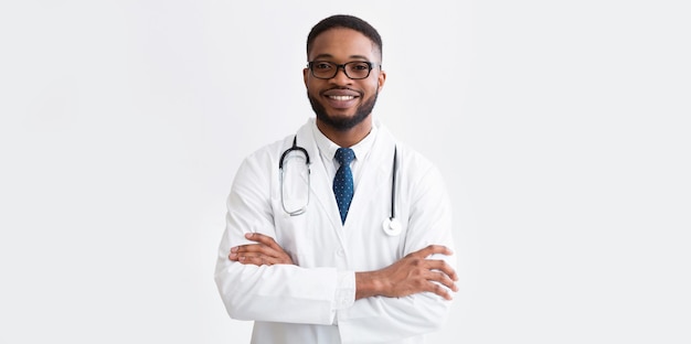 Médico feliz en uniforme blanco contra un fondo claro con panorama del espacio de copia