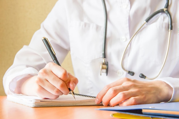 Médico femenino escribe en cuaderno en el desc