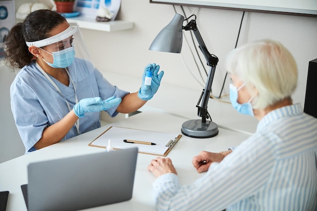 Médico femenino sugiriendo botella azul de gotas