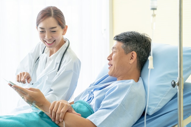 Médico feminino asiático, sentar-se cama hospital, e, discutir, com, paciente sênior