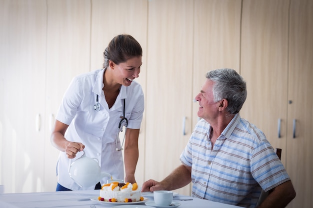 Médico feminino celebração idosos homem aniversário na sala de estar