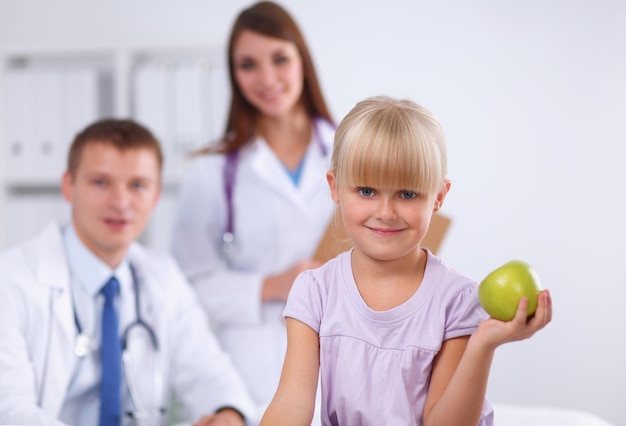 Médico feminino do conceito de criança e medicina dando uma maçã para uma garotinha sorridente