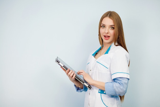 Médico feminino feliz usando o tablet pc isolado em um fundo branco. Linda garota com um jaleco branco. Copie o espaço