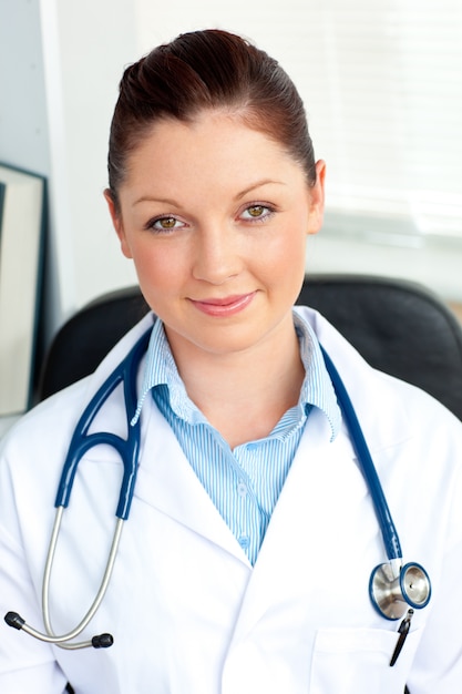 Médico feminino seguro de si mesmo sorrindo para a câmera sentado