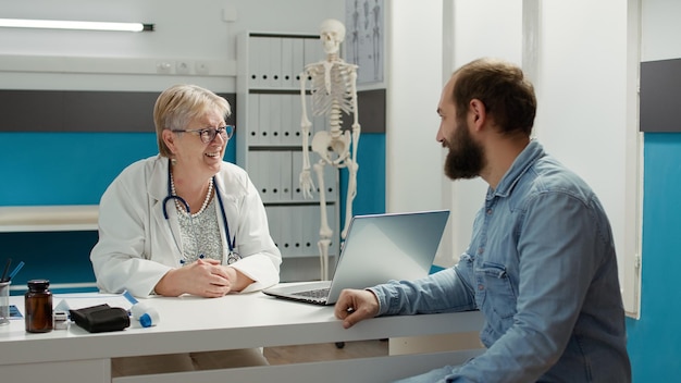 Médico general haciendo consulta de chequeo con paciente masculino, examinando la atención médica del hombre con enfermedad. Médico conversando sobre tratamiento y recuperación con un adulto joven.