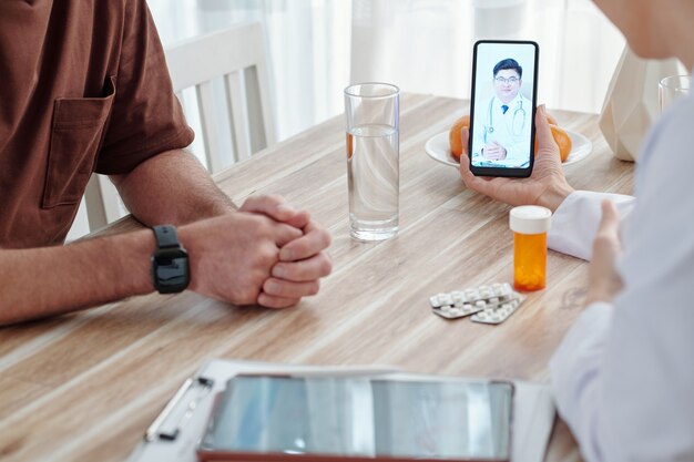 Médico general que organiza videollamadas con otro especialista cuando habla con el paciente en su consultorio.