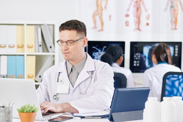 Médico general trabajando en equipo portátil