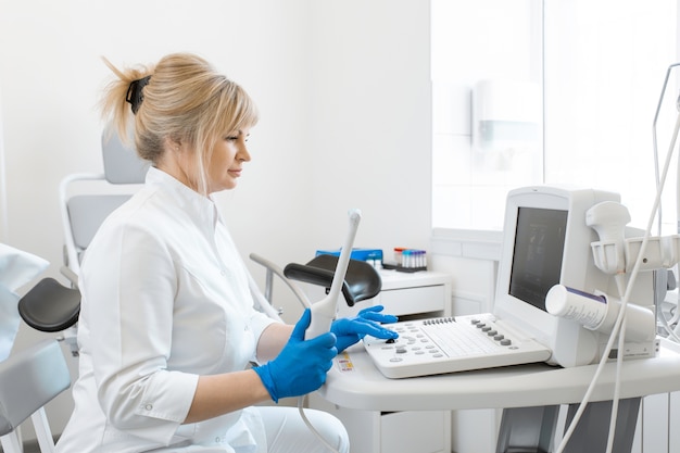 Médico ginecologista prepara máquina de ultrassom para o diagnóstico do paciente