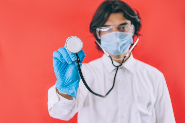 Un médico con guantes azules y un protector facial y un endoscopio en rojo
