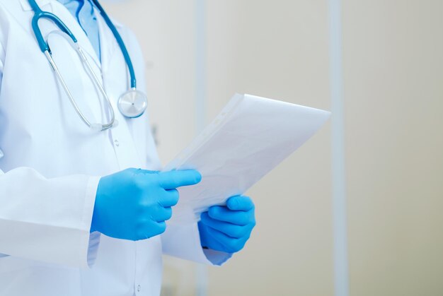 Foto médico con guantes de látex azul con documentación médica tema de atención médica