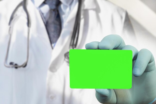 Un médico con guantes médicos azules sostiene una tarjeta de visita frente a él Closeup Fondo con espacio de copia Tarjeta de visita en blanco para texto