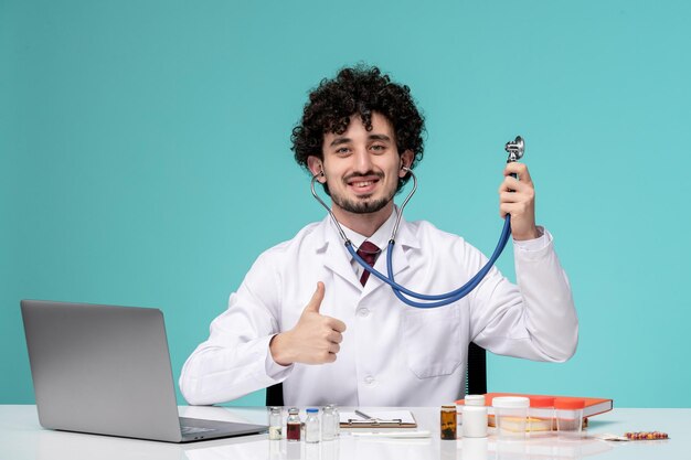 Médico guapo lindo médico trabajando en la computadora de forma remota en bata de laboratorio con estetoscopio